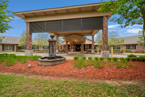 A welcoming entrance featuring a fountain and landscaped garden under a clear blue sky.
