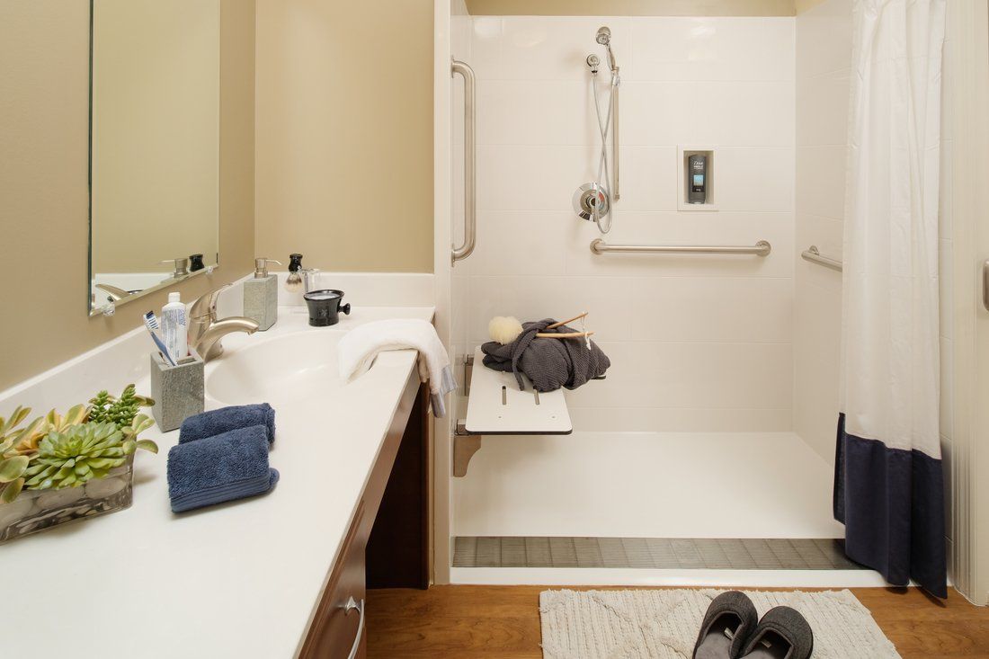 An accessible bathroom with a shower featuring a grab bar and a foldable seat.