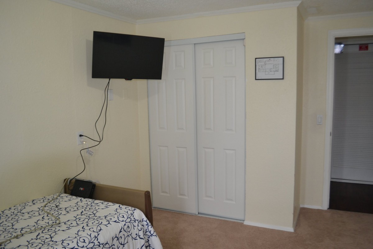 A minimalist bedroom with a wall-mounted TV and a closed closet.