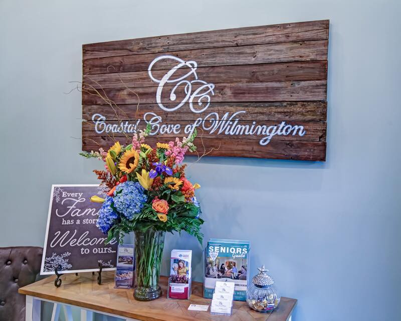 A beautifully decorated reception area with a wooden sign and a vibrant bouquet of flowers.