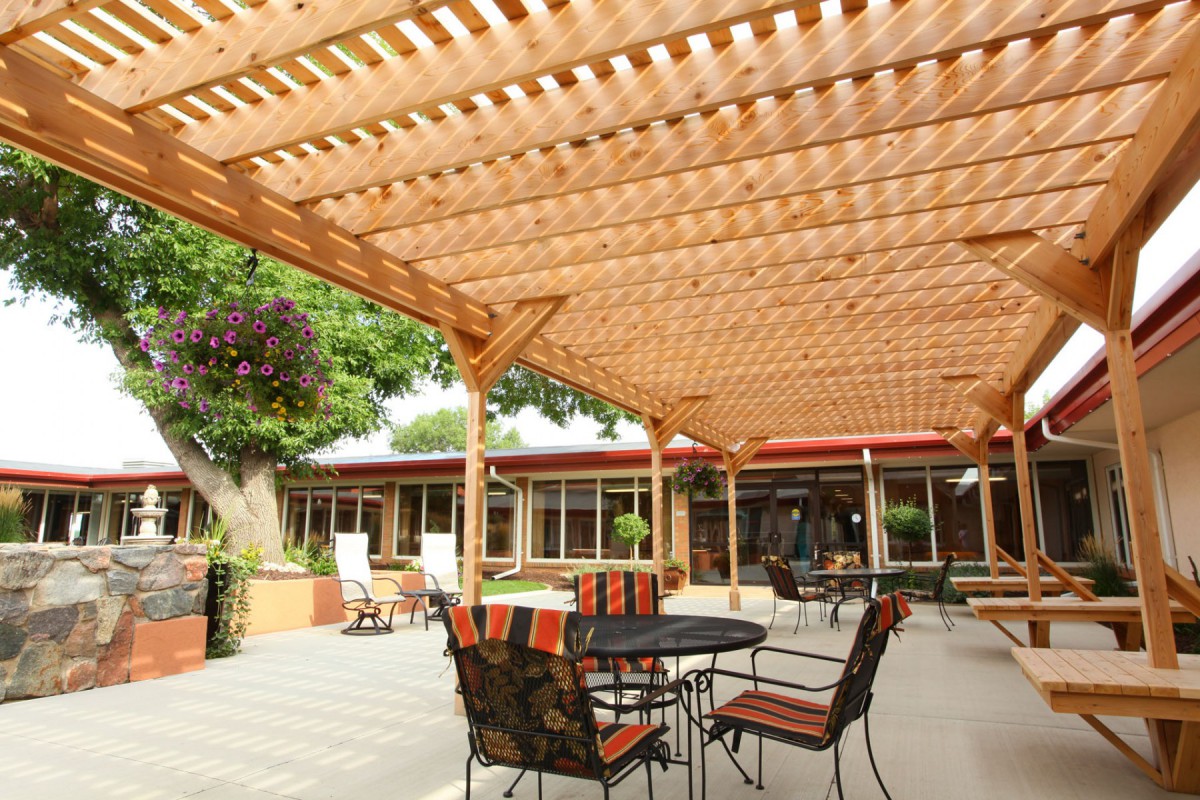 A sunny patio with a wooden pergola and outdoor seating area.