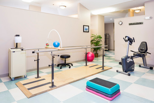 A well-equipped physical therapy room featuring a balance bar, exercise equipment, and a vibrant atmosphere.