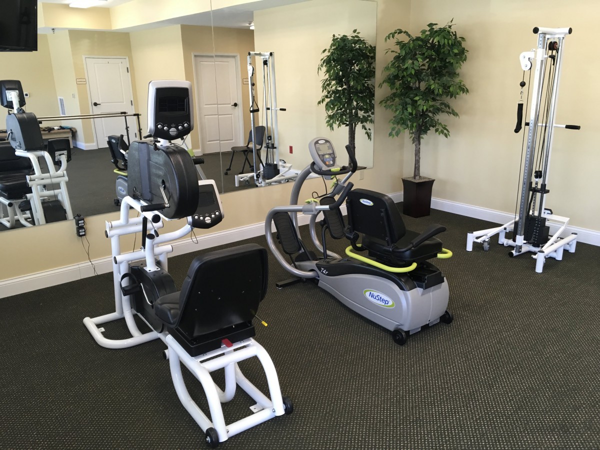 A gym room equipped with various exercise machines and cardio equipment.