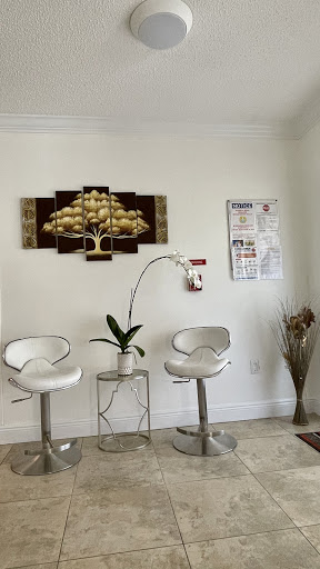 A modern waiting area featuring stylish chairs, a decorative wall piece, and a small plant.