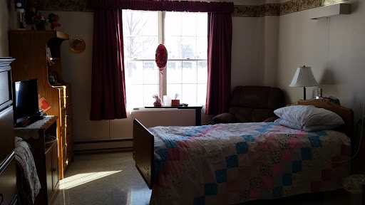 A cozy bedroom with a neatly made bed and natural light streaming through the window.