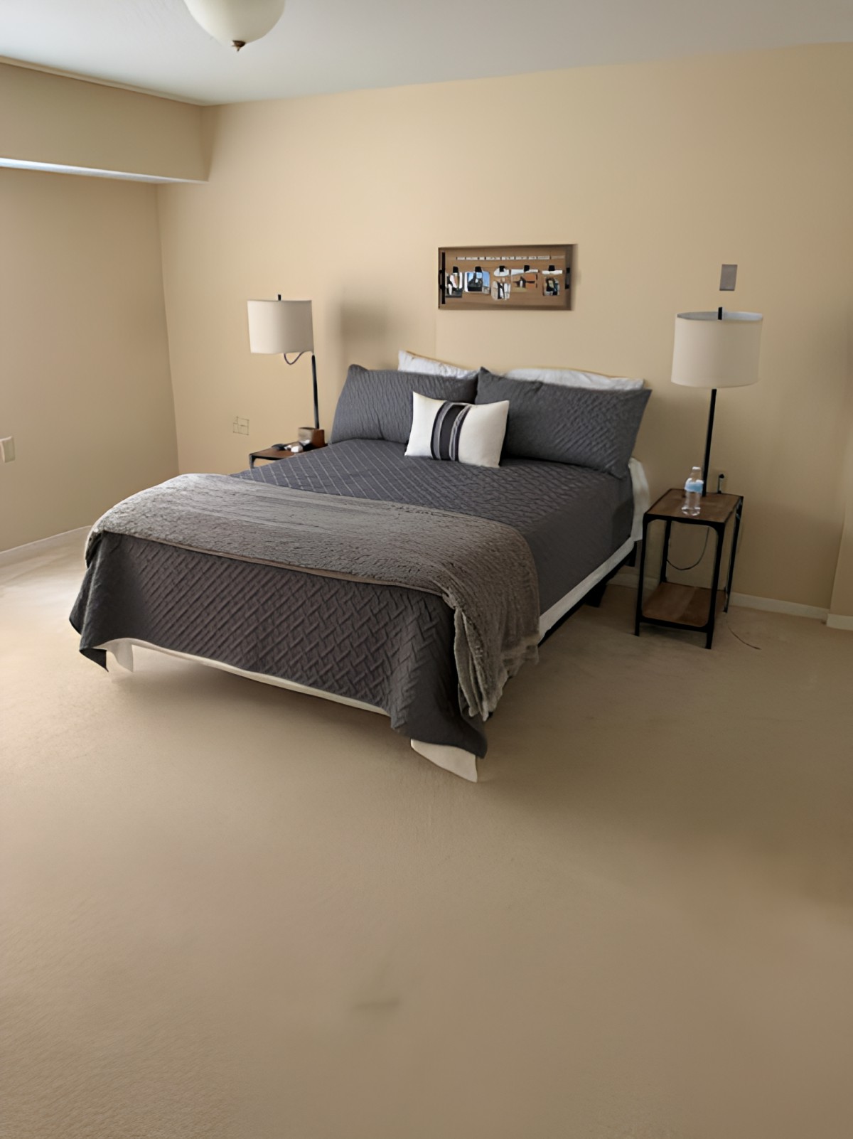 A tidy and well-decorated bedroom with a large bed, two lamps, and neutral tones.