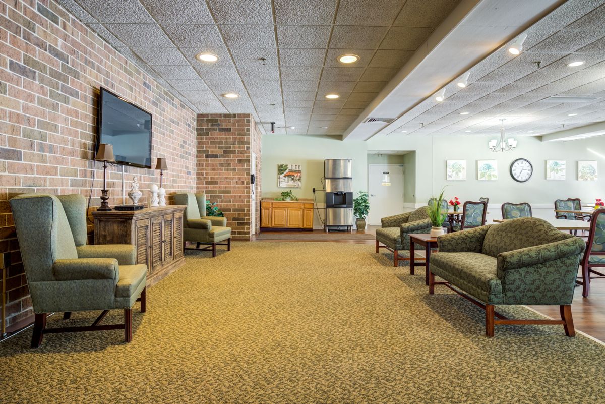 A spacious lobby or waiting room with comfortable seating and a television on the wall.