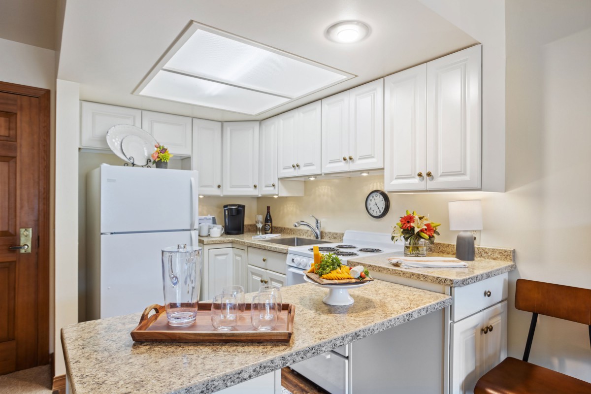 A modern kitchen with white cabinets and a well-lit countertop area.