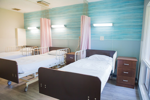 A serene hospital room with two neatly made beds, promoting a calm healing environment.