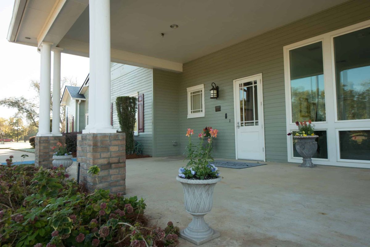 A welcoming house entrance with a porch, potted plants, and white columns.
