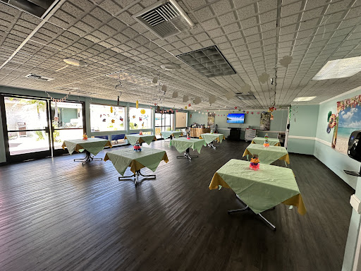 A spacious, empty restaurant setting with green tablecloths and a modern interior.