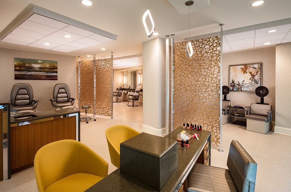 A modern salon interior featuring stylish chairs and a well-lit nail station.