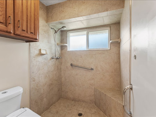 A spacious and accessible bathroom featuring a modern shower design with tiled walls.