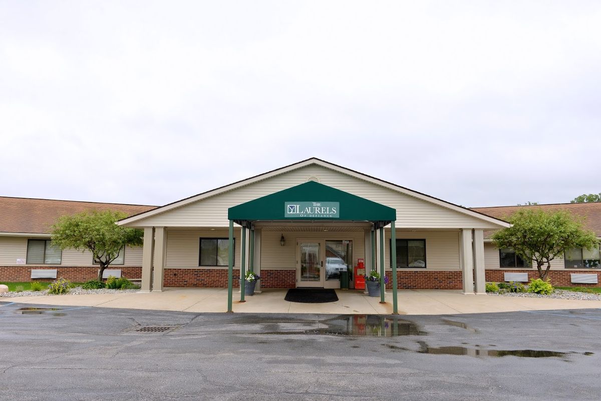 A building with a green awning over the entrance, located in a parking lot.