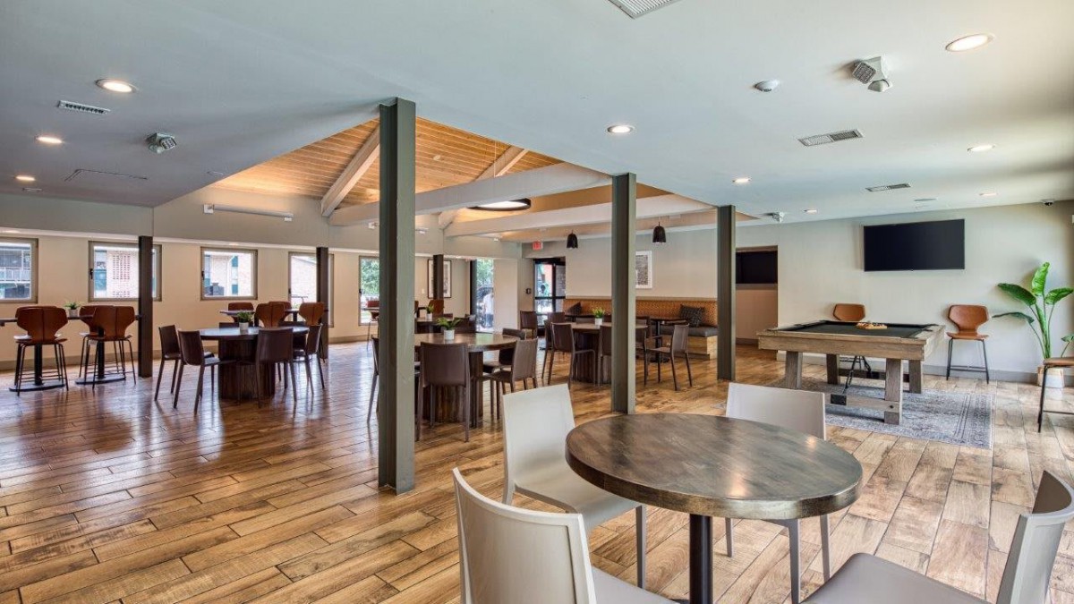 A spacious restaurant interior with wooden flooring and multiple seating arrangements.