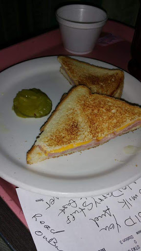 A crispy grilled cheese sandwich served with a side of pickle.