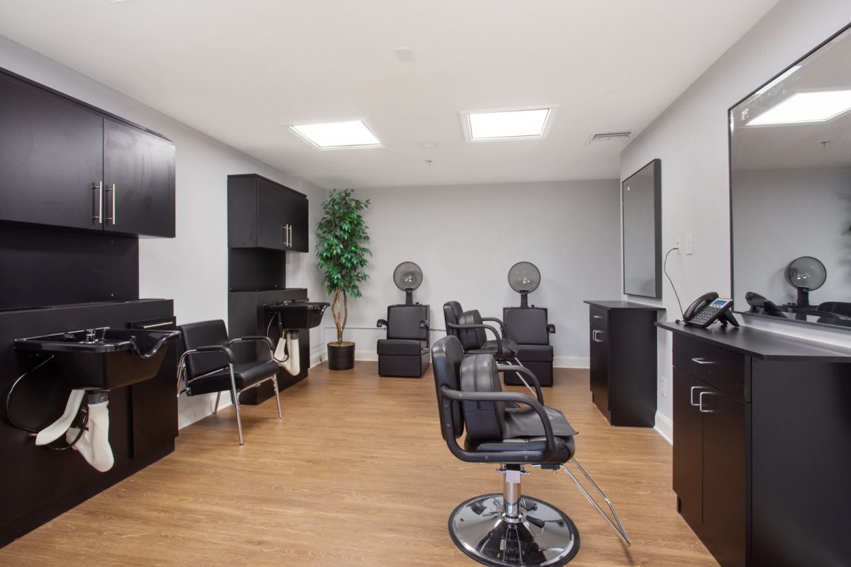 A modern hair salon interior featuring multiple styling stations and sleek black chairs.