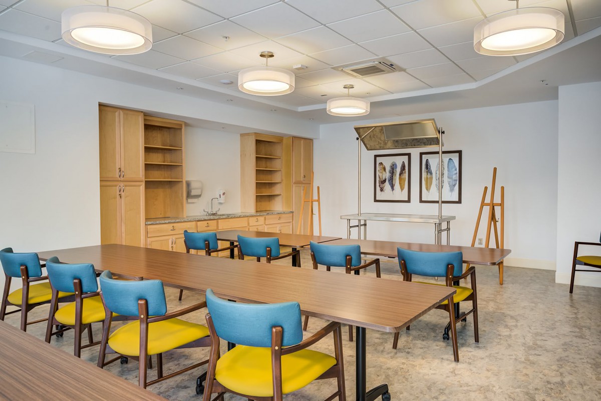 A modern conference room with colorful chairs, wooden tables, and contemporary lighting.