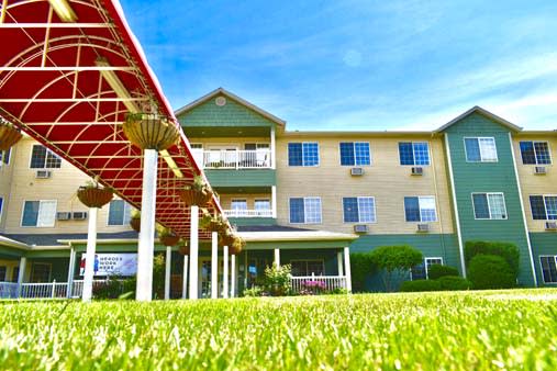 A low-angle view of a building with a lush green lawn under a bright blue sky.