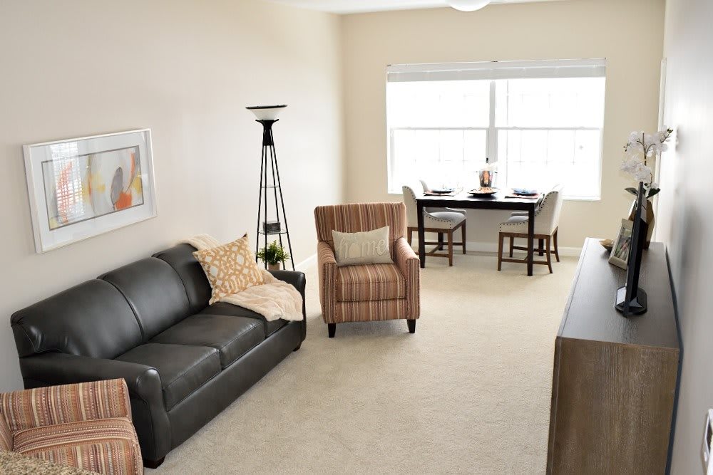 A cozy living room with a sofa, armchair, and dining area.
