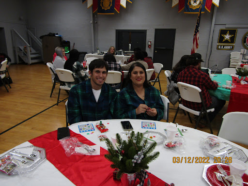 A couple enjoying a festive event, dressed in matching plaid outfits at a cheerful holiday gathering.