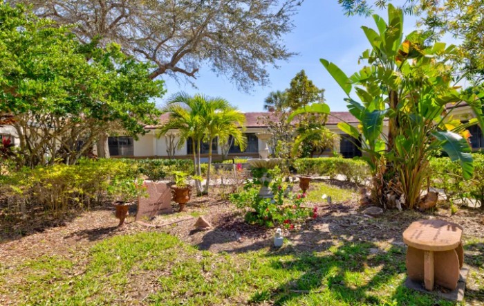 A beautifully landscaped garden with tropical plants and palm trees in front of a residential building.