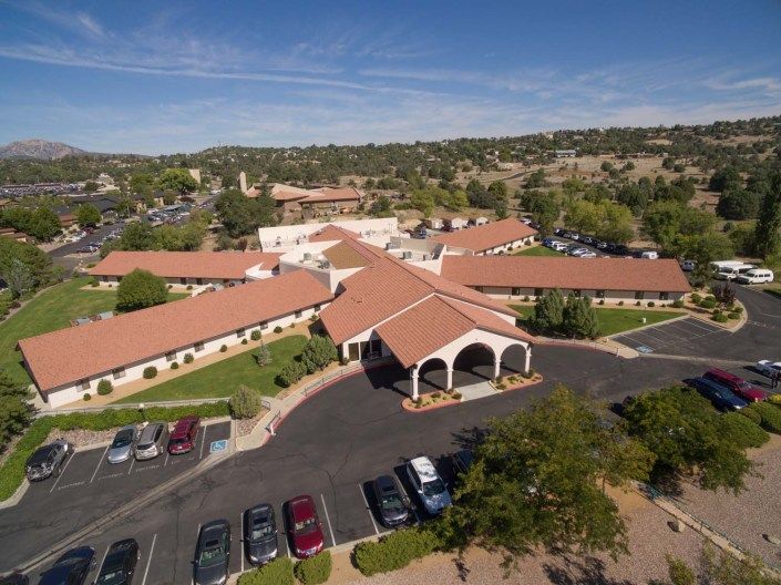 An aerial view of a community building with a parking lot and surrounding landscape.