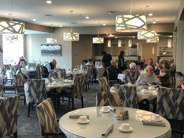 A dining area with several tables and people seated, featuring modern lighting and decor.