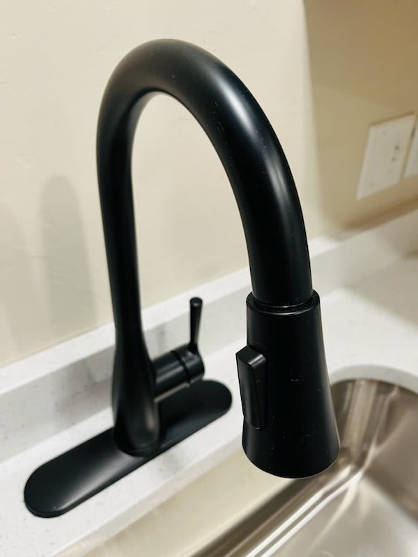 A modern black kitchen faucet installed over a sink.