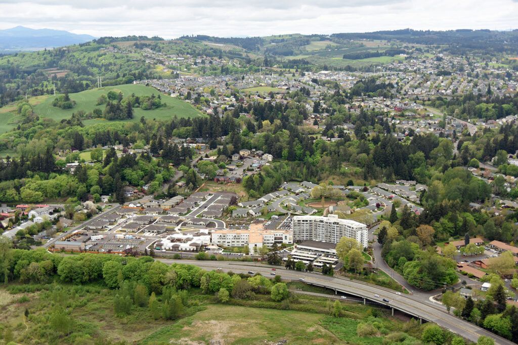 A scenic aerial view of an urban area surrounded by green hills and roads.