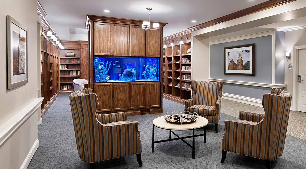 Cozy library seating area featuring an aquarium and wooden bookshelves.
