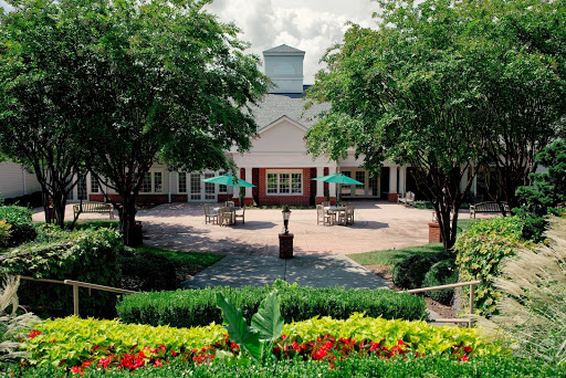 A serene courtyard featuring lush greenery and vibrant flowers, set against the backdrop of a charming building.