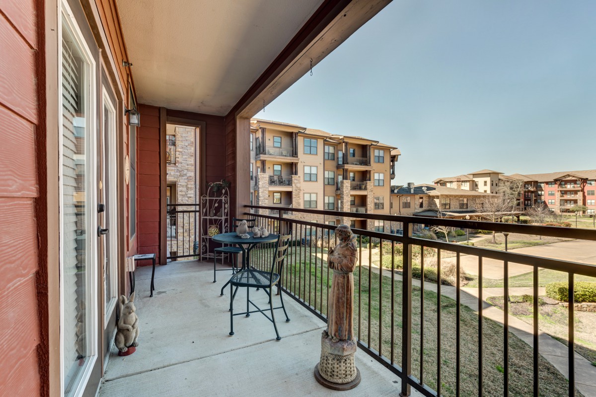 A comfortable balcony with seating, offering a view of nearby apartment buildings.