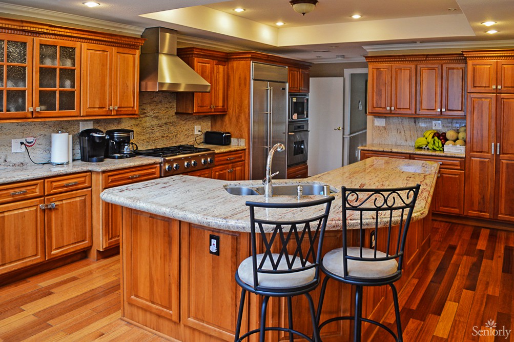 A modern kitchen with wood cabinets, granite countertops, and stainless steel appliances.