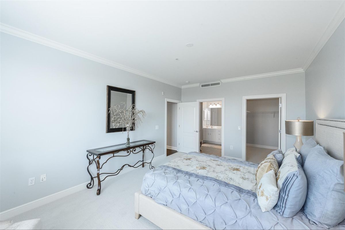 A bright and spacious minimalist bedroom featuring a comfortable bed and elegant furniture.