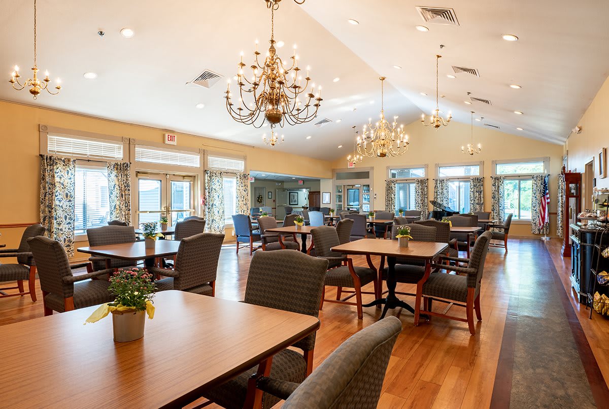 A spacious and elegantly decorated dining room with multiple tables and chandeliers.