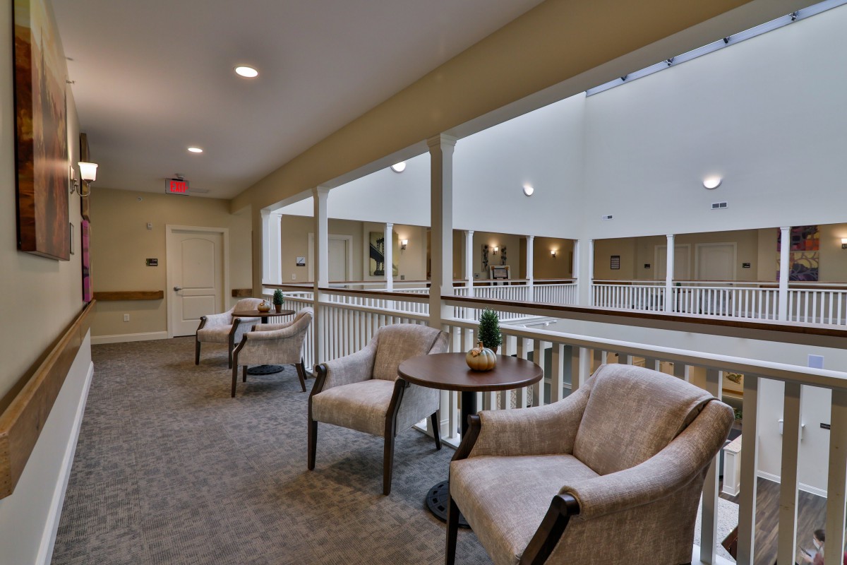 A quiet seating area with comfortable chairs and a table in an indoor corridor.