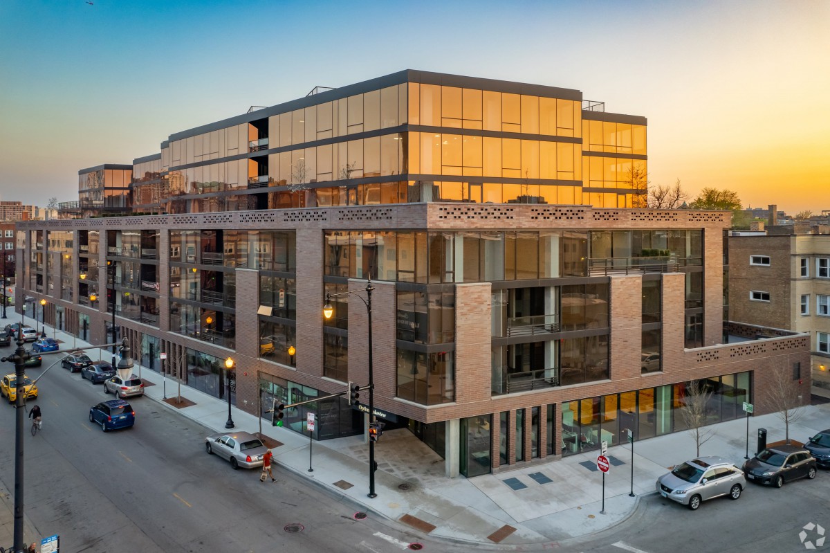 A modern urban building illuminated by the warm glow of a sunset.