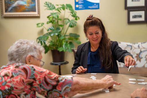 A caregiver and an elderly individual enjoy a game together, fostering companionship and engagement.
