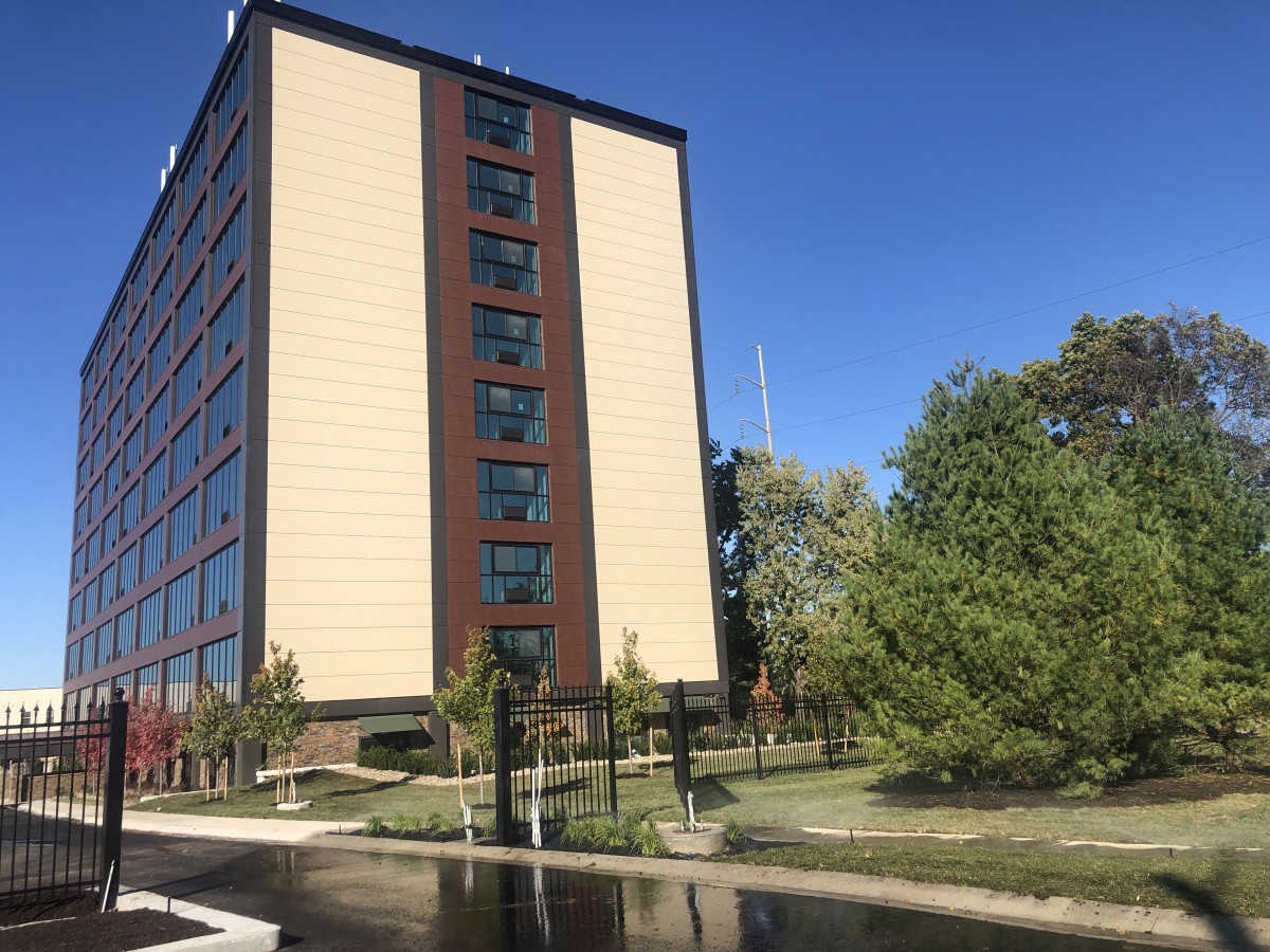 A tall building surrounded by trees under a clear blue sky.
