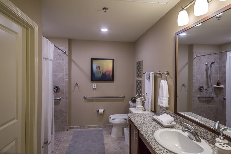 A modern bathroom with a spacious layout, featuring a sink, shower area, and neatly arranged towels.