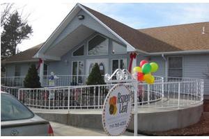 A building with a sloped roof, adorned with colorful balloons and a sign near the entrance.