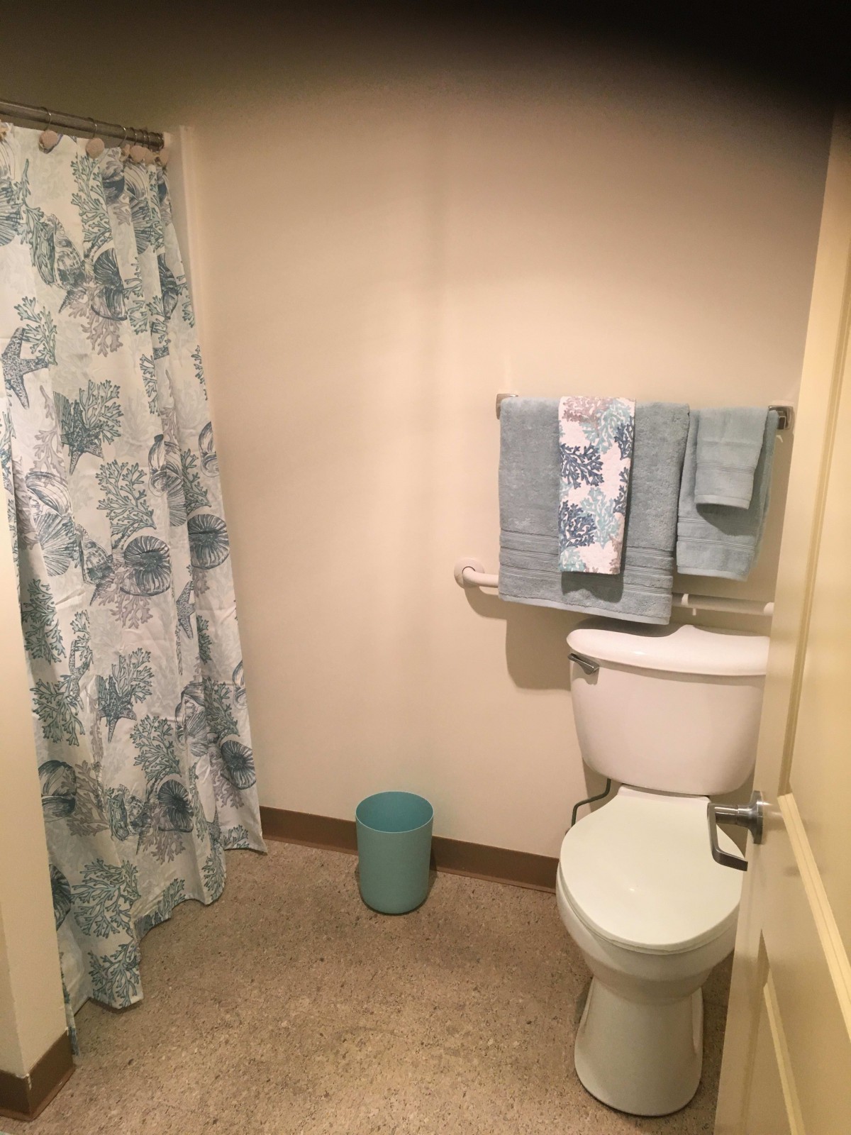 A neatly arranged bathroom with a patterned shower curtain and matching towels.