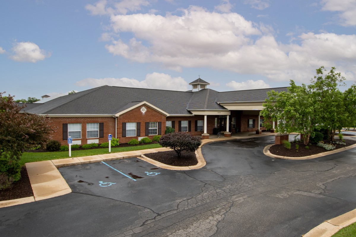 A single-story brick building with a parking lot and accessible parking spaces under a cloudy sky.