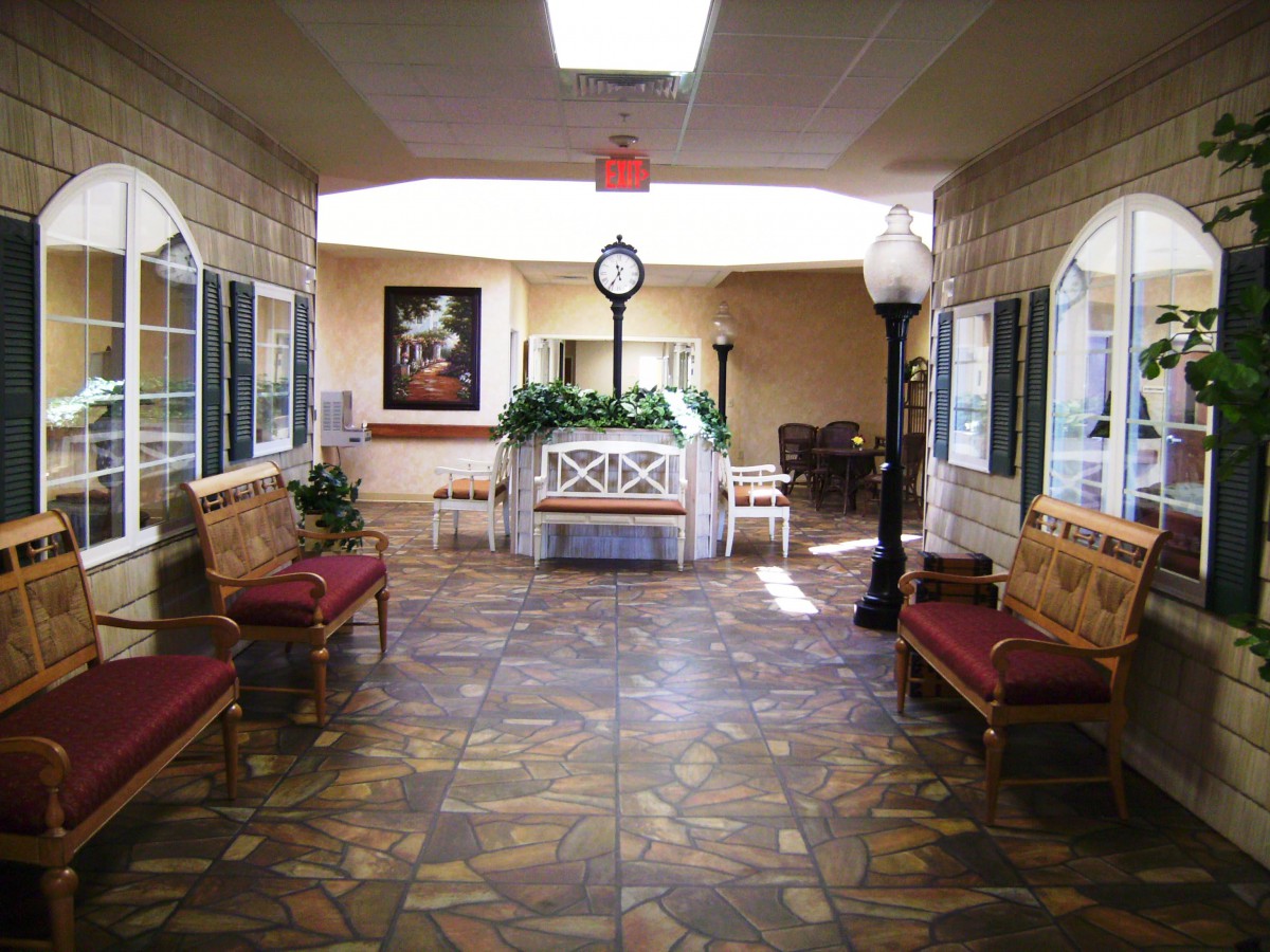 A spacious lobby with benches, a central clock, and decorative plants.