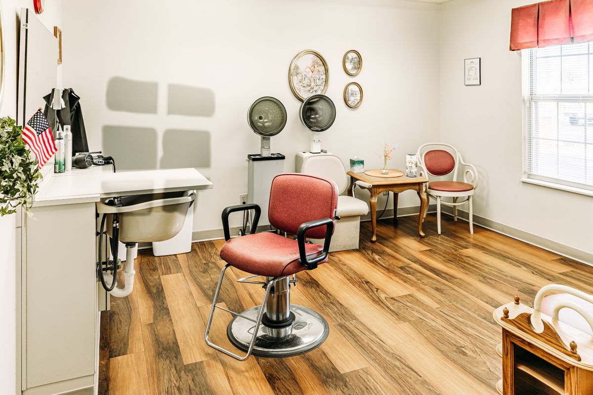 A vintage-style hair salon with a red barber chair, wood flooring, and retro decor.