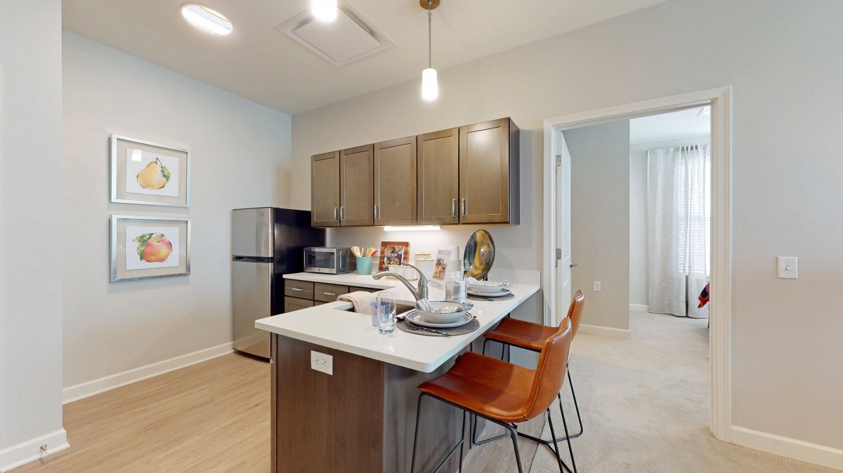 A modern kitchen with wooden cabinets, stainless steel appliances, and a bar counter with seating.