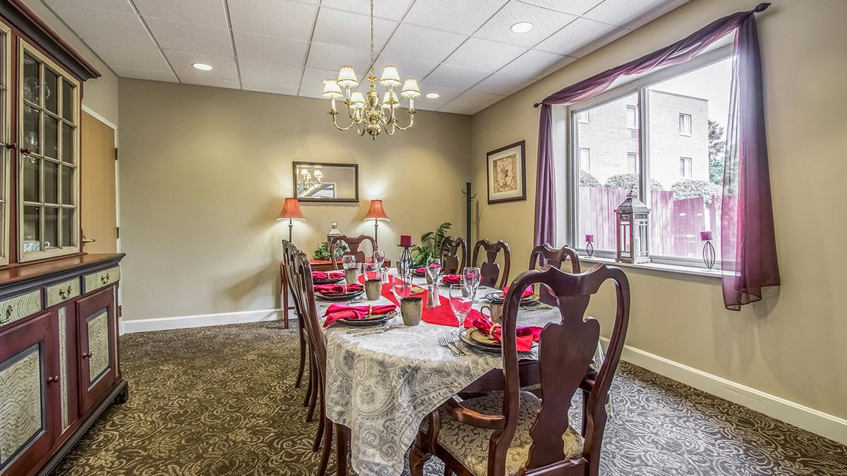 An elegant dining room with a long table set for a meal, featuring a chandelier and decorative elements.
