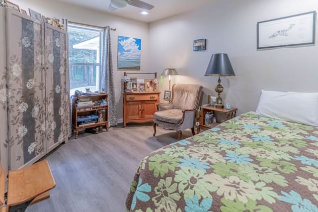 A cozy bedroom with a floral bedspread, a comfortable chair, and various decorations.