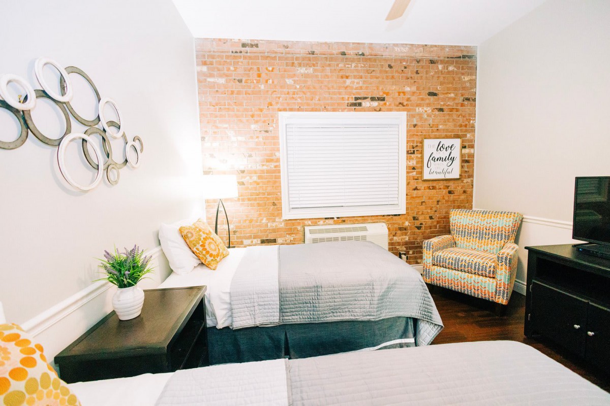 A cozy bedroom with a brick accent wall, featuring a neatly made bed and stylish decor.